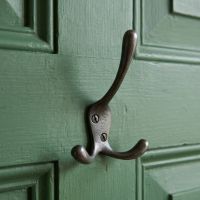 The Blacksmith Vintage Cast Iron Three-Prong Hall Hook - 100mm Mounted on a Green Door - Digital Illustration