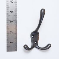 The Blacksmith Vintage Cast Iron Three-Prong Hall Hook - 100mm On a White Background  next to a Ruler - Digital Illustration