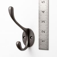 The Cotswold Circular Backplate Cast Iron Coat Hook 110mm on a White Background next to a Steel Ruler for Scale - Digital Illustration