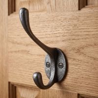 The Cotswold Circular Backplate Cast Iron Coat Hook 110mm Shown Mounted on the Back of a Wooden Door - Digital Illustration