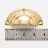 The Cotswold Round Lipped Cup Pull Handle in Brass on a White Background next to a Steel Ruler for Scale - Digital Illustration