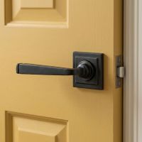 The Dickinson House Beeswax Unsprung Lever Door Handle on Square Rose on a Bright Yellow Door in a Modern Home Interior - Digital Illustration