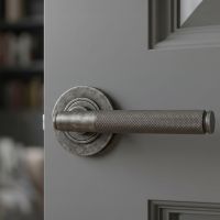 The Edmond Gardens Pewter Textured Lever Door Handle on Rose Mounted on a Grey Door Shown up Close - Digital Illustration