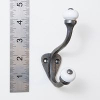 The Estate White Porcelain Knob Iron Coat Hook on a White Background next to a Steel Ruler for Scale - Digital Illustration