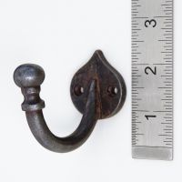 The Forge Antique Iron Single Peg Wall Hook on a White Background next to a Steel Ruler for Scale - Digital Illustration