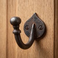 The Forge Antique Iron Single Peg Wall Hook Shown Mounted onto a Wooden Door - Digital Illustration