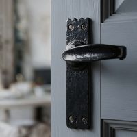 The Gallio Curved Cast Iron Lever Handle Shown Close up Mounted on a Grey Door - Digital Illustration