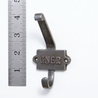 The GNER Railway Double Coat Hook in Cast Antique Iron next to a Ruler On a White Background  - Digital Illustration