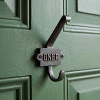 The GNER Railway Double Coat Hook in Cast Antique Iron Shown on the Rear of a Green Door - Digital Illustration