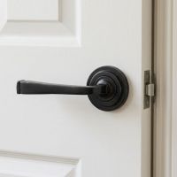 The Grayson Manor Midnight Black Unsprung Lever Door Handle on Art Deco Rose Shown Mounted on a Bright White Door - Digital Illustration