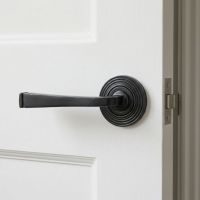 The Grayson Manor Midnight Black Unsprung Lever Door Handle on Beehive Rose On a Bright White Door Shown Close up - Digital Illustration