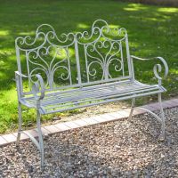 The Grey "Belvedere" Wrought Iron Garden Bench in a Sunny Garden on a Gravel Path