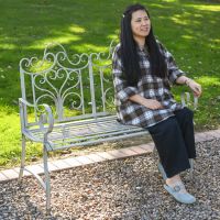 The Grey "Belvedere" Wrought Iron Garden Bench with a Lady Sat on the Bench for Scale