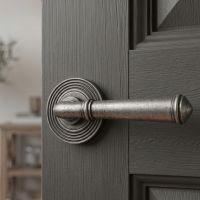 The Hadley Gardens Antique Pewter Unsprung Lever Door Handle on Beehive Rose Shown Close up and mounted on a Grey Door - Digital Illustration