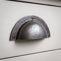 The Half-Moon Cast Antique Iron Cup Pull Handle - 110mm Shown Close up on a Grey Drawer - Digital Illustration