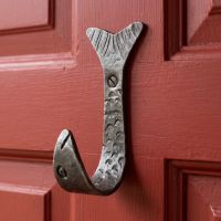 The Hand-Forged Fish Single Coat Hook - 110mm Mounted onto a Red Door Shown Close up - Digital Illustration