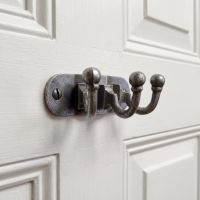 The Hawthorn Triple Coat Hook in Cast Antique Iron - 35 x 90mm on a White Door Shown Close up - Digital Illustration
