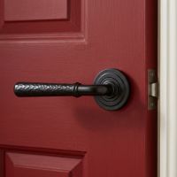 The Hunter Lodge Midnight Black Hammered Unsprung Lever Door Handle on Art Deco Rose Shown Mounted onto a Red Door in a Country Home - Digital Illustration