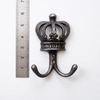 The Imperial Crown Cast Iron Double Coat Hook on a White Background next to a Steel Ruler for Scale - Digital Illustration