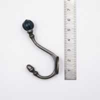 The Ironmonger Acorn Dark Green Ceramic Coat Hook - 125mm on a White Background next to a Steel Ruler for Scale - Digital Illustration