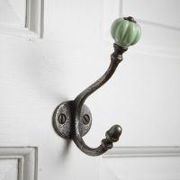 The Ironmonger Acorn Light Green Ceramic Coat Hook - 125mm Shown Mounted on the Back of a White Door - Digital Illustration