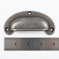 The Ironmonger Crescent Cup Pull 47mm x 102mm on a White Background next to a Steel Ruler for Scale - Digital Illustration