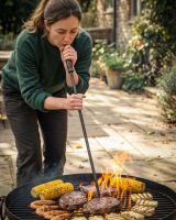 The Kadai Fire Blow Pipe & Stoking Poker with a Lady Shown Blowing through the Pipe to Stoke the Fire in a Fire Pit - Digital Illustration