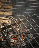 The Kadai Hand-Forged 6-Piece Skewer Set with Elevated Rack Showing a Close up of the Skewer Tips above a Lit Grill - Digital Illustration