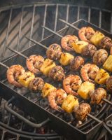 The Kadai Hand-Forged 6-Piece Skewer Set with Elevated Rack Showing a Close up of the Skewers used to Grill Prawn Kebabs - Digital Illustration