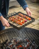 The Kadai Hand-Forged 6-Piece Skewer Set with Elevated Rack Shown in a Sunny Garden Patio next to a Fire Bowl - Digital Illustration