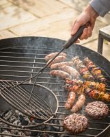 The Kadai Iron Grill Lifter with Hardwood Handle Shown Being used to Lift a Grill on a Kadai Bowl - Digital Illustration