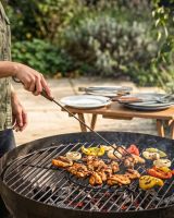 The Kadai Long-Handled Open Fire Toasting Fork Shown Being Used to Cook Food Over a Kadai Bowl and Grill - Digital Illustration
