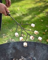 The Kadai Marshmallow Roasting Branch with Wooden Handle Shown being Held over a Firepit and Grill - Digital Illustration