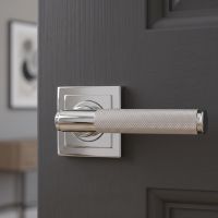 The Knurled Sprung Handle Set on a Square Rose in Polished Stainless Steel on an Open Door in a Modern Home - Digital Illustration