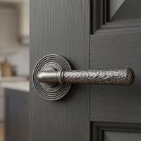 The Landen House Aged Pewter Hammered Unsprung Lever Door Handle on Beehive Rose Shown Close up on a Dark Grey Door to a Kitchen - Digital Illustration