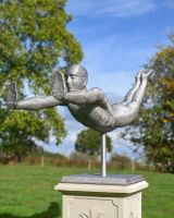 The Leap of Faith Contemporary Garden Statue on a Raised Plinth in a Sunny Garden