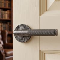 The Locke House Aged Pewter Textured Unsprung Lever Door Handle on Beehive Rose in a Traditional Home on a Classic Cream Coloured Door - Digital Illustration