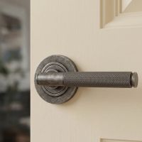 The Locke House Aged Pewter Textured Unsprung Lever Door Handle on Rose on a Cream Coloured Door Shown Close up - Digital Illustration