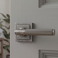 The Locke House Aged Pewter Textured Unsprung Lever Door Handle on Square Rose on a Light Grey Door in a Modern Home - Digital Illustration