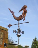 The Maritime Mermaid Verdigris Copper Weathervane Shown at a Low Angle Mounted on a Wall