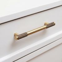 The Medium Half Knurled Cabinet Pull Handle in Aged Brass Shown on a White Set of Drawers in a Modern Interior - Digital Illustration