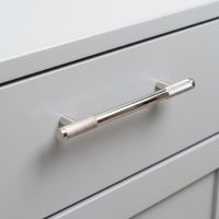 The Medium Half Knurled Cabinet Pull Handle in Polished Nickel on a Sleek Grey Drawer Shown Close Up - Digital Illustration