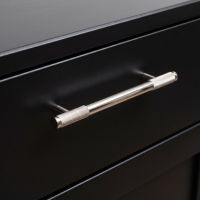 The Medium Half Knurled Cabinet Pull Handle in Polished Stainless Steel on a Black Set of Drawers in a Modern Kitchen - Digital Illustration