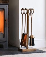 The Middleton Hammered Antique Brass Companion Set next to a Modern Hearth in a Living Room - Digital Illustration
