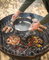 The Set of 3 Kadai Iron BBQ Skillet Pan Set Shown with the Medium Skillet Being Placed onto a Grill - Digital Illustration