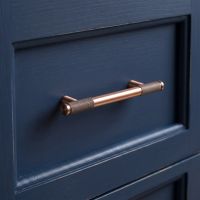 The Small Half Knurled Cabinet Pull Handle in Polished Bronze on a Navy Blue Kitchen Drawer - Digital Illustration