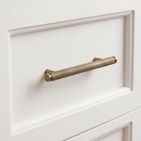 The Small Knurled Cabinet Pull Handle in Aged Brass Fitted on a Wooden Drawer in a Modern Home - Digital Illustration