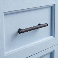 The Small Knurled Cabinet Pull Handle in Aged Bronze on a light Blue Set of Wooden Drawers - Digital Illustration