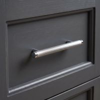 The Small Knurled Cabinet Pull Handle in Polished Chrome Displayed in a Modern Kitchen on a Wooden Drawer - Digital Illustration