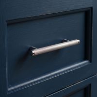 The Small Knurled Cabinet Pull Handle in Polished Stainless Steel on a Blue Drawer in a Modern Kitchen - Digital Illustration